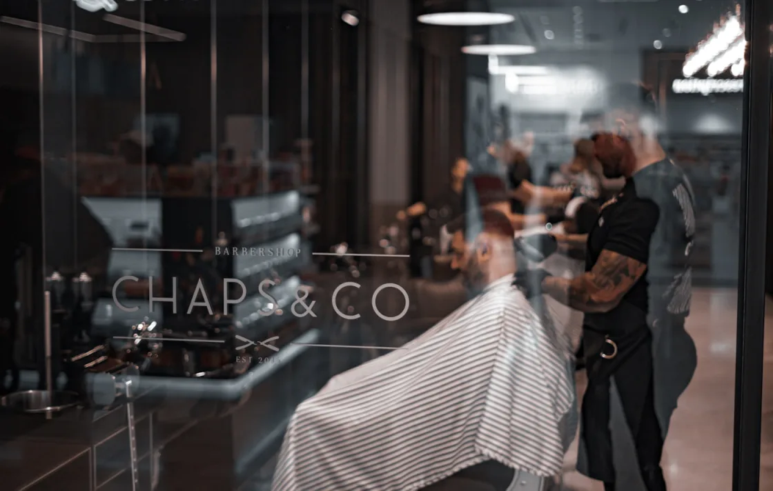 Barber giving a client a haircut inside a modern barbershop that takes online appointments with SlotPress
