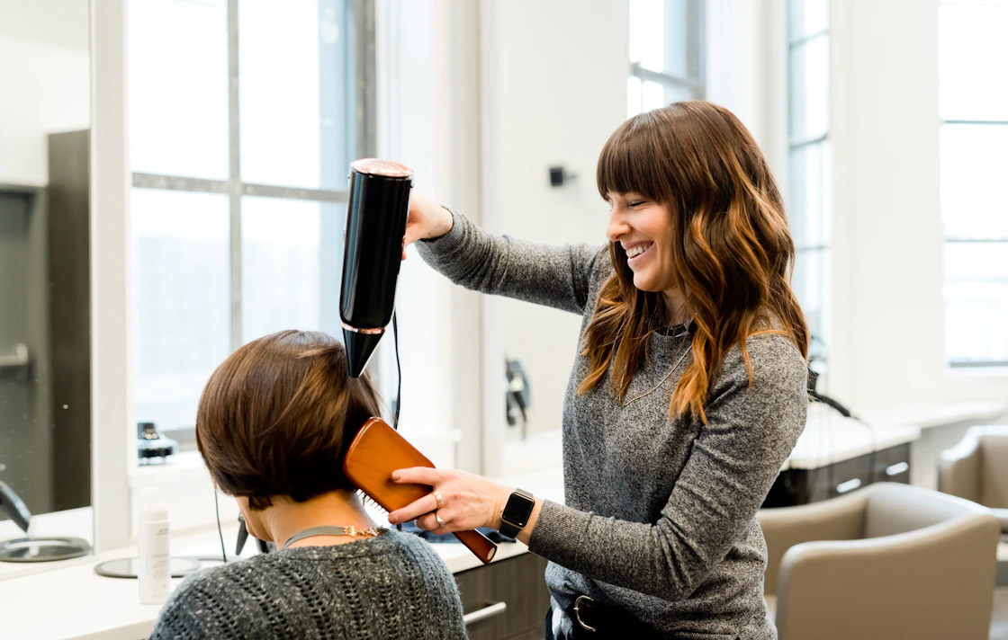 Hairstylist applying colour to a client's hair in a modern salon using SlotPress for online appointment bookings